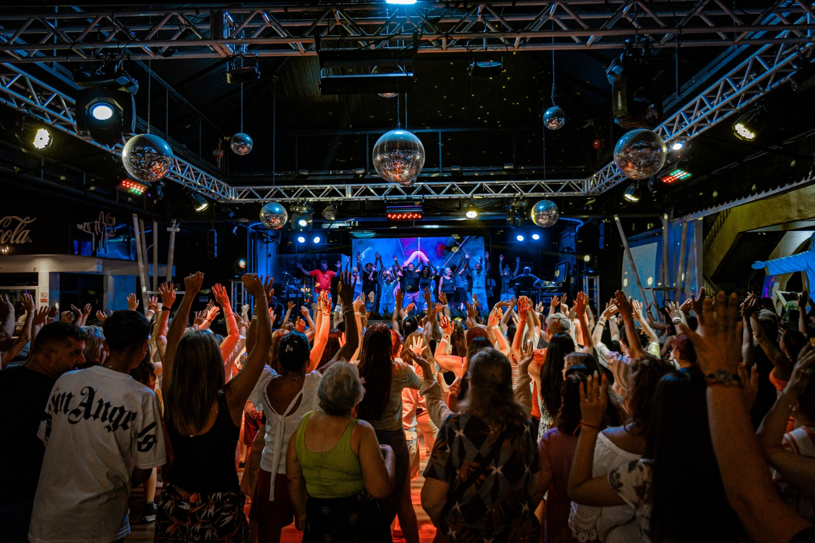 Pista de dança iluminada, com varias pessoas dançando.